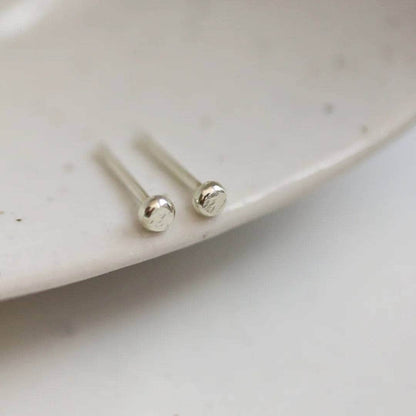 Tiny 9ct white gold dot stud earrings on the edge of a dish