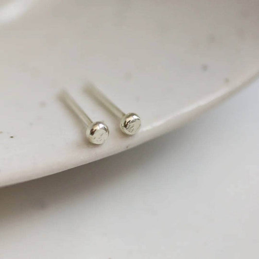 Tiny 9ct white gold dot stud earrings on the edge of a dish