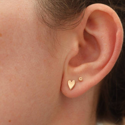 Tiny gold studs with star design modelled in the second piercing with gold heart studs 
