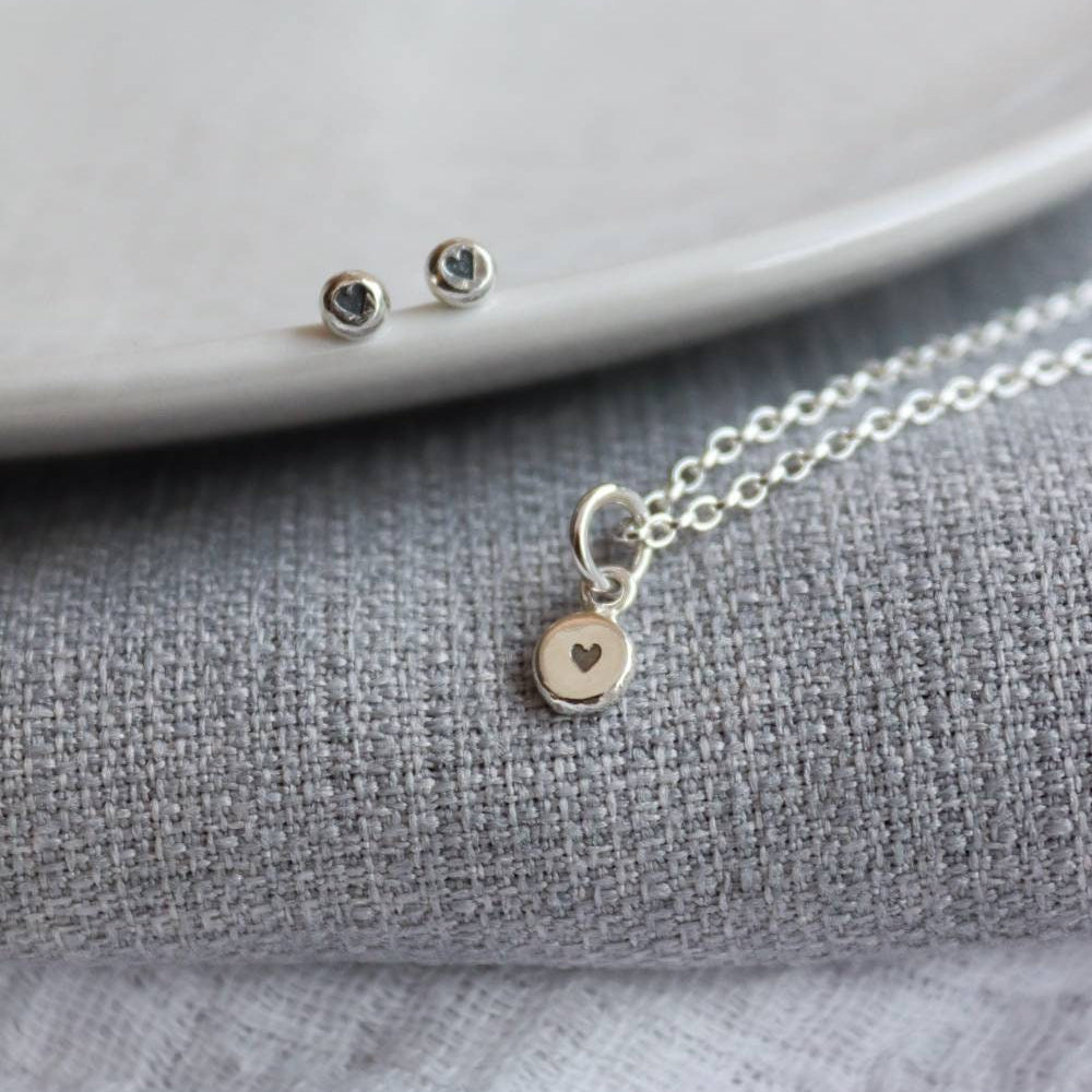 a pair of heart stamped stud earrings and a silver chain with a heart stamp pendant in the centre.