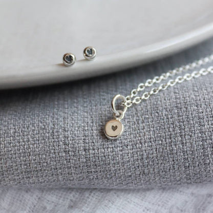 a pair of heart stamped stud earrings and a silver chain with a heart stamp pendant in the centre.