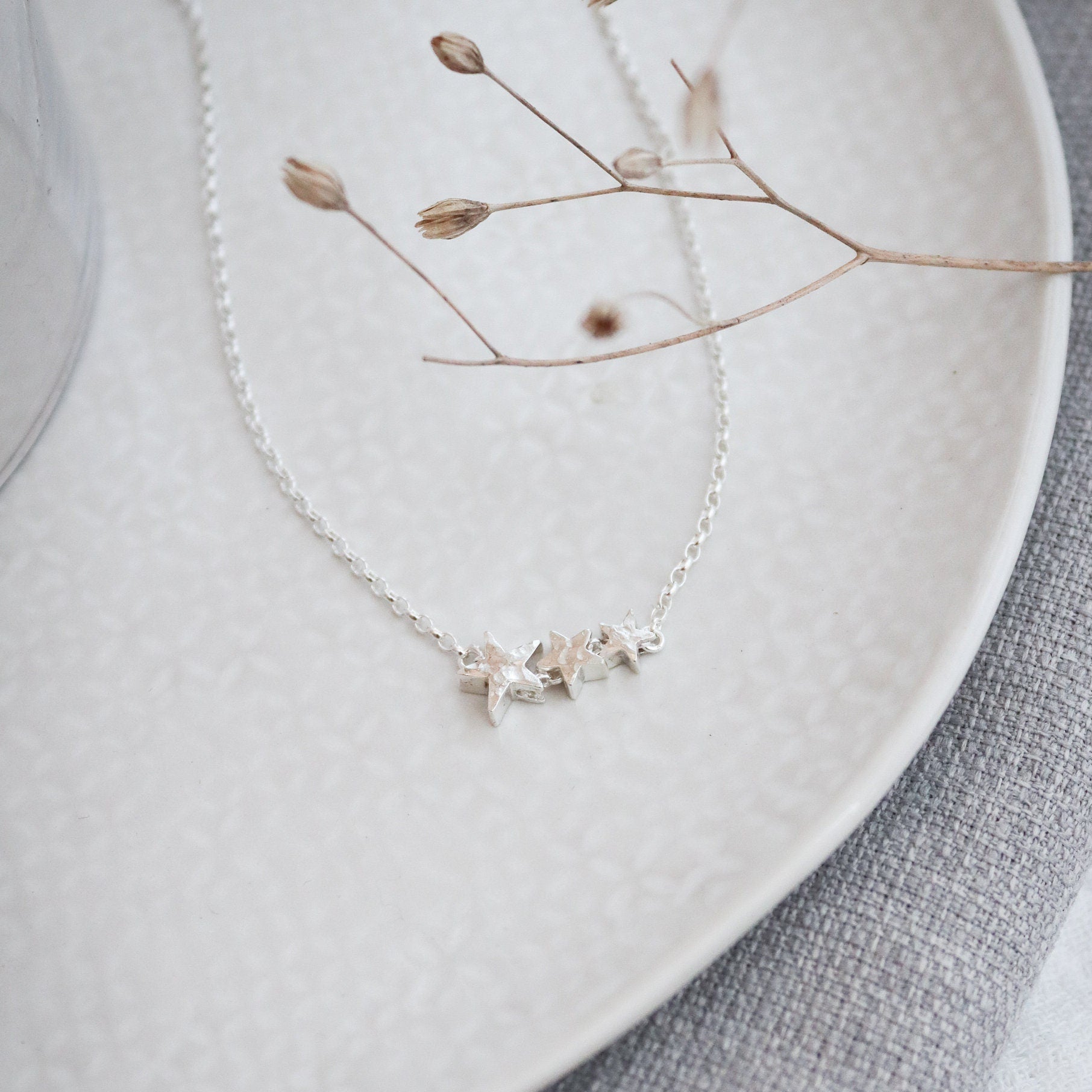 silver necklace with 3 silver stars big to small with a hammered finish.