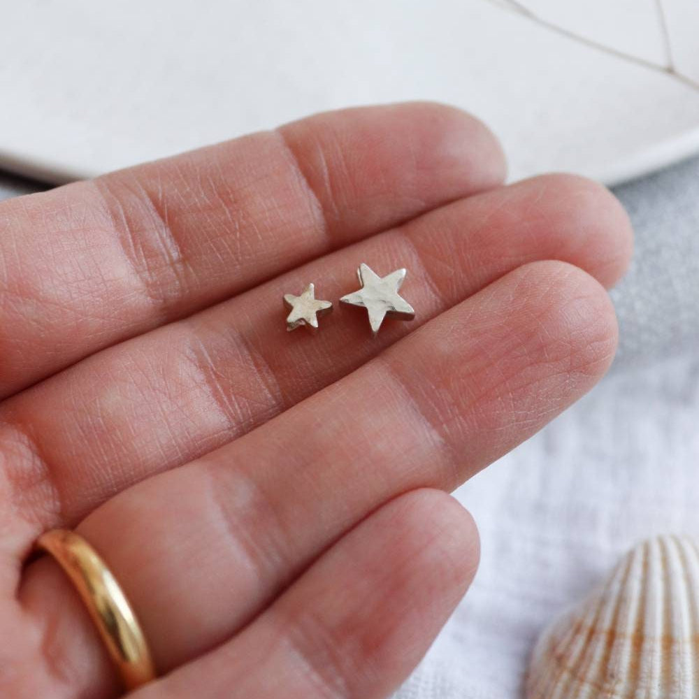 silver star beads shown held in a hand to show two sizes of star before personalisation.