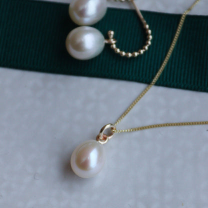 A gold pearl necklace with a diamond cut curb chain and a pearl drop, presented against a white background.