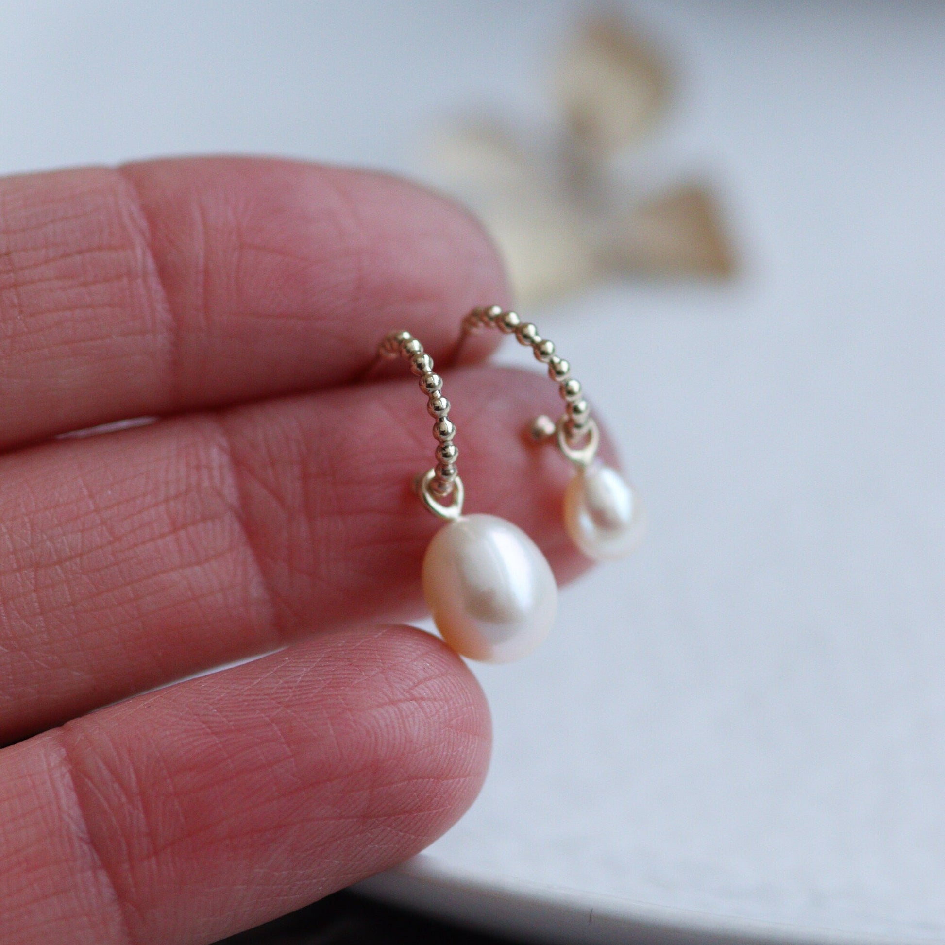 gold huggie hoops with two sizes of pearl drop