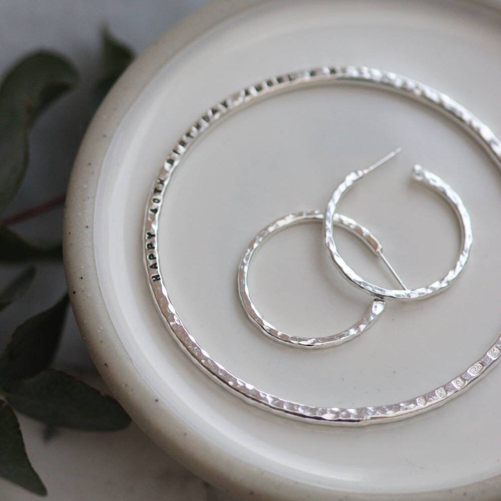 hammered silver jewellery, a bangle with a message engraved and silver hoop earrings.
