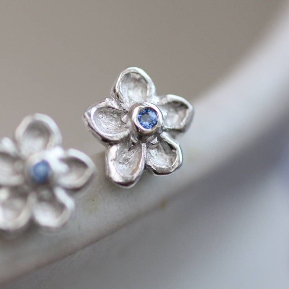silver forget-me-not stud earrings with blue sapphire stone centres