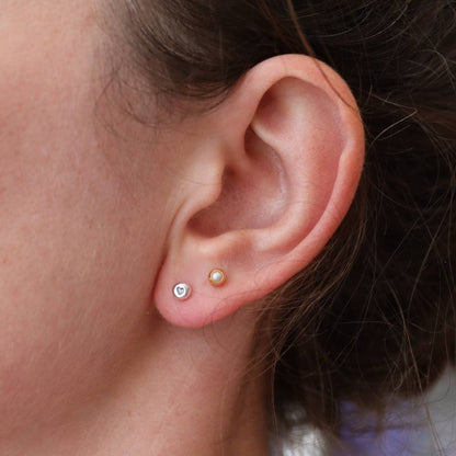 Small Silver stud earrings with heart design worn in a first piercing.