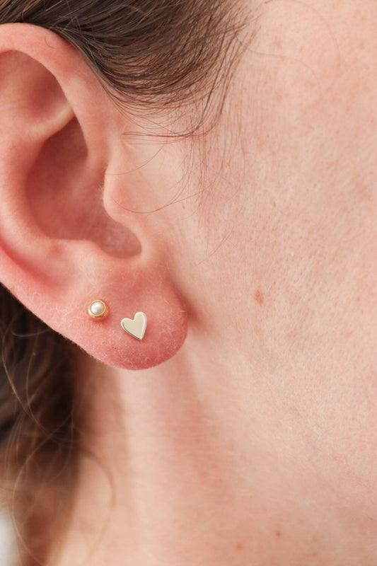 Little Silver heart studs shown in an ear