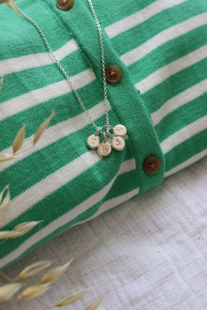 Initial stamped pebble pendants in a cluster on a striped jumper