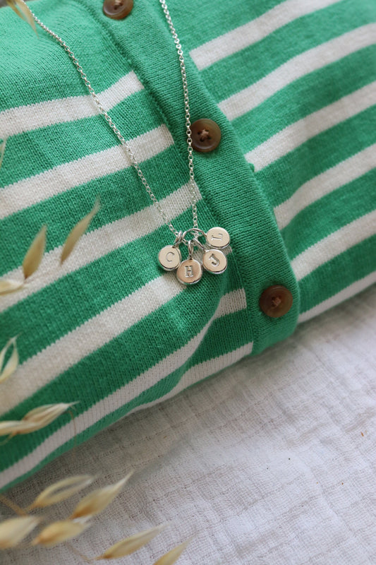Initial stamped pebble pendants in a cluster on a striped jumper