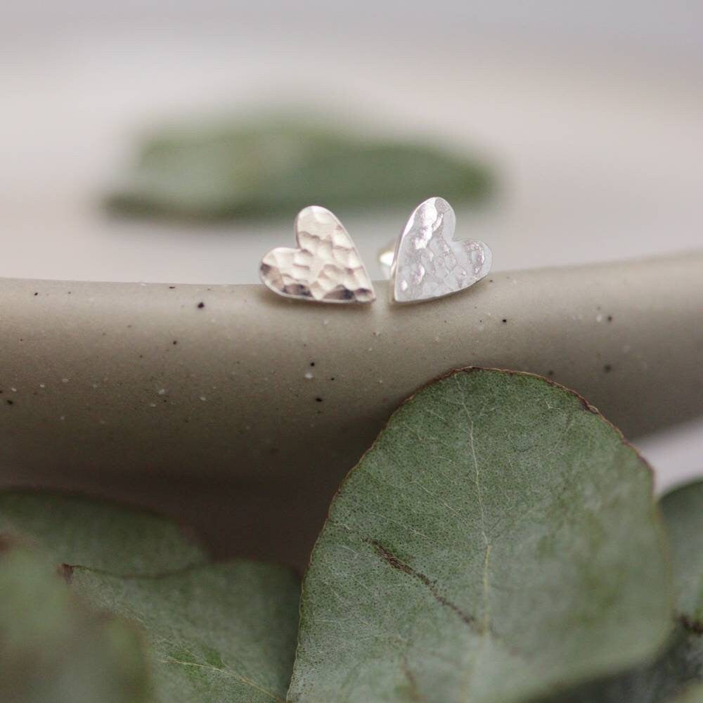 silver heart studs with a hammered texture on a ceramic dish.