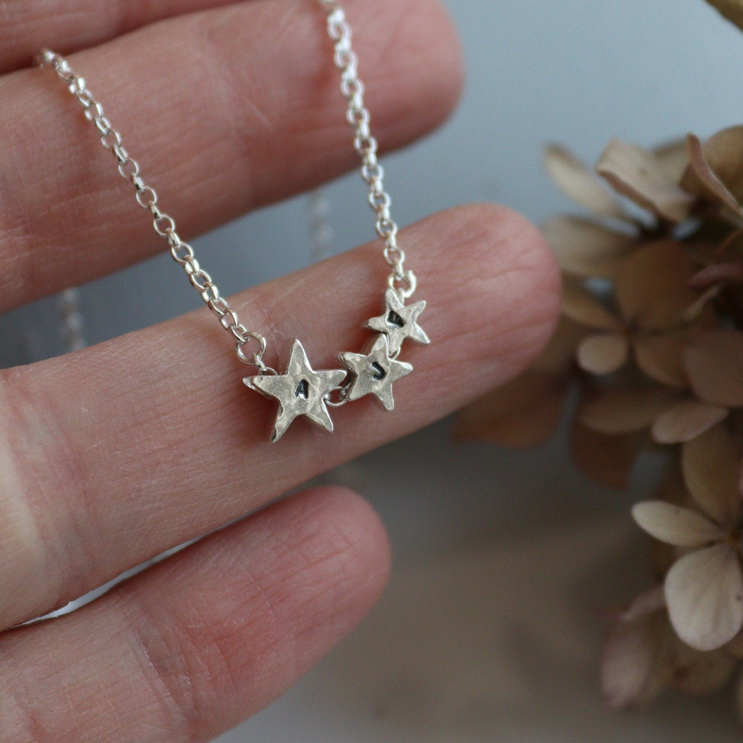 3 silver stars with personalised initials with a hammered finish on a silver chain.