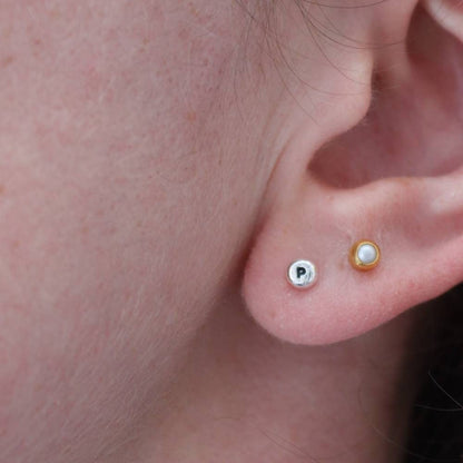 Tiny silver stud earring with a letter p initial stamped and blackened for contrast against the shiny silver.