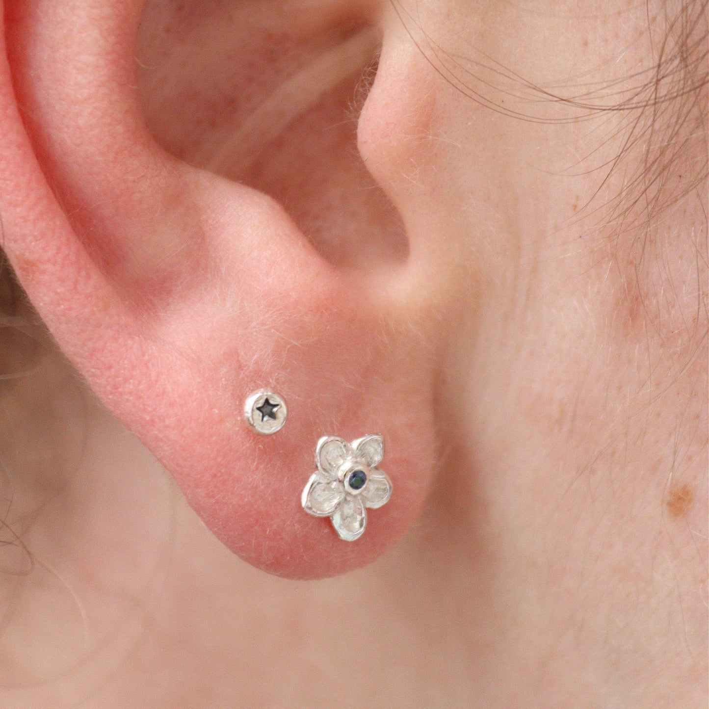 silver forget-me-not studs being worn in an earlobe