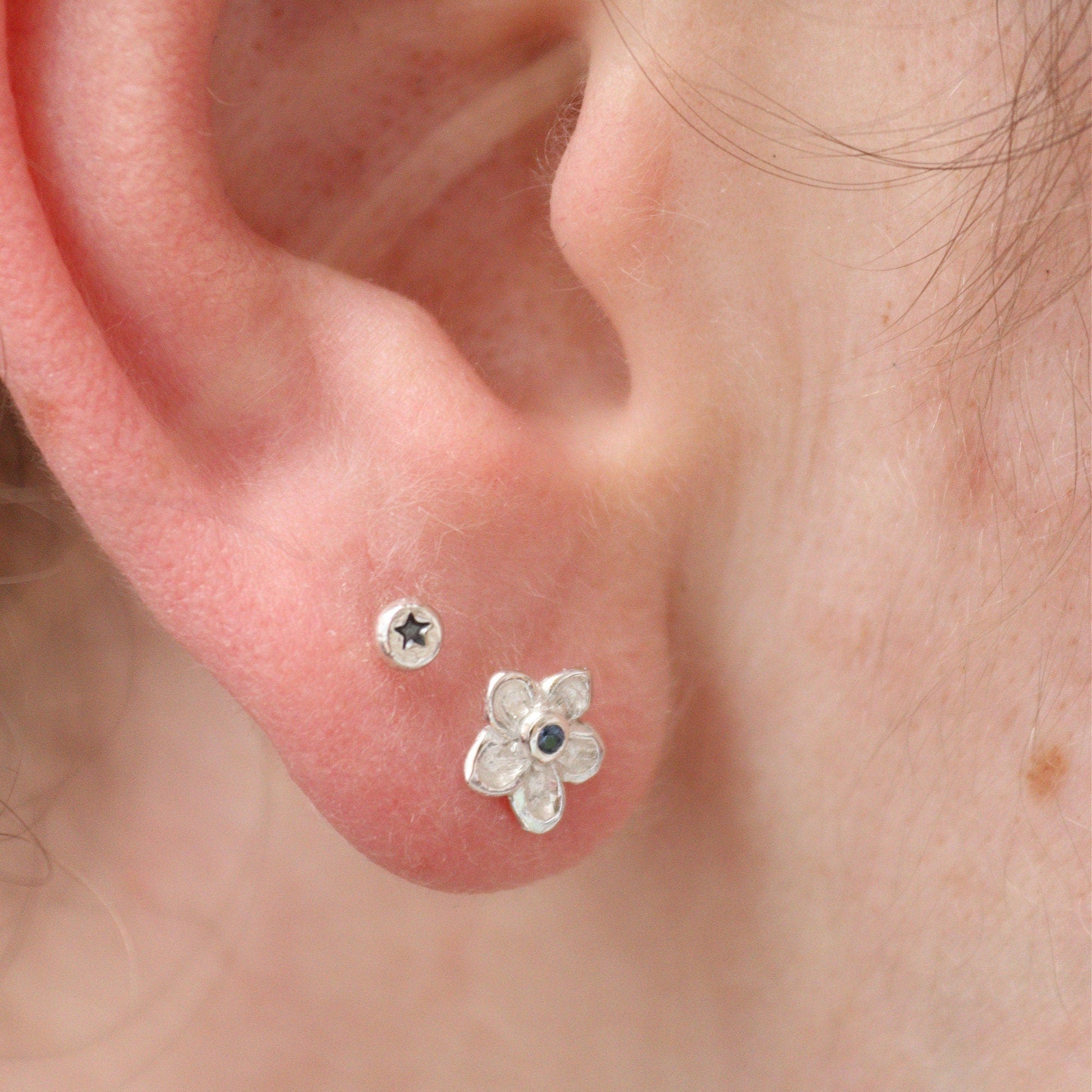 silver forget-me-not studs being worn in an earlobe