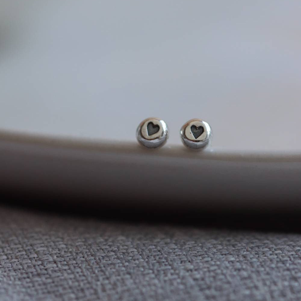 Silver stud earrings with an oxidised (blackened) heart design impressed into them.