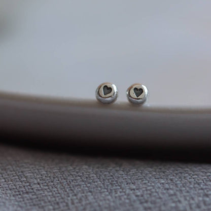 Silver stud earrings with an oxidised (blackened) heart design impressed into them.