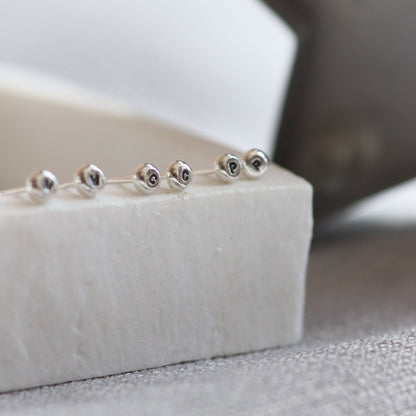 A line up of silver studs with initials stamped into them.