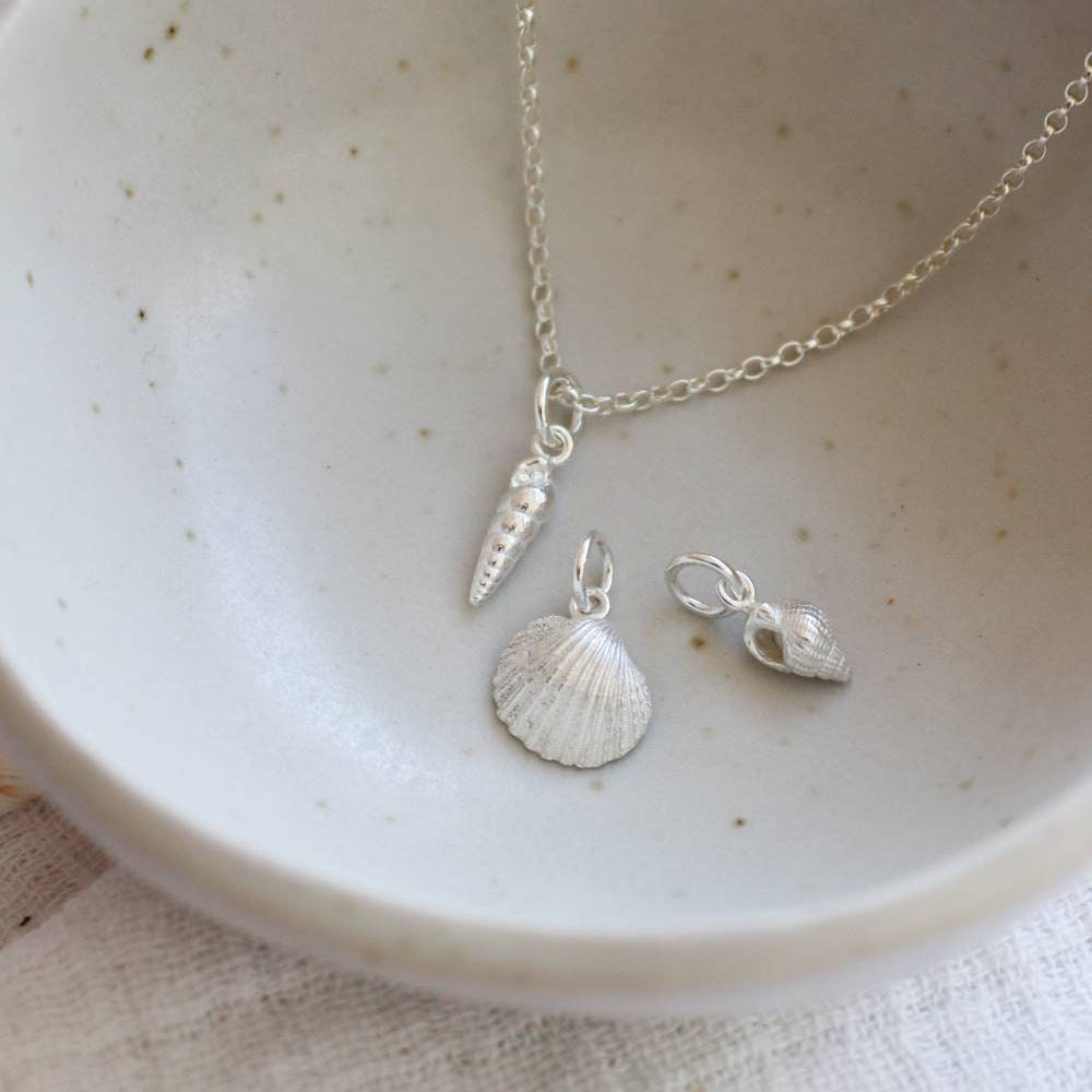 silver seashell charms, spiral shell, cornish cockle and dorset whelk in a bowl.