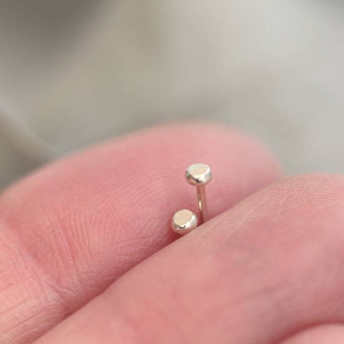 Tiny 2.5mm 9ct white gold dot studs in between fingers